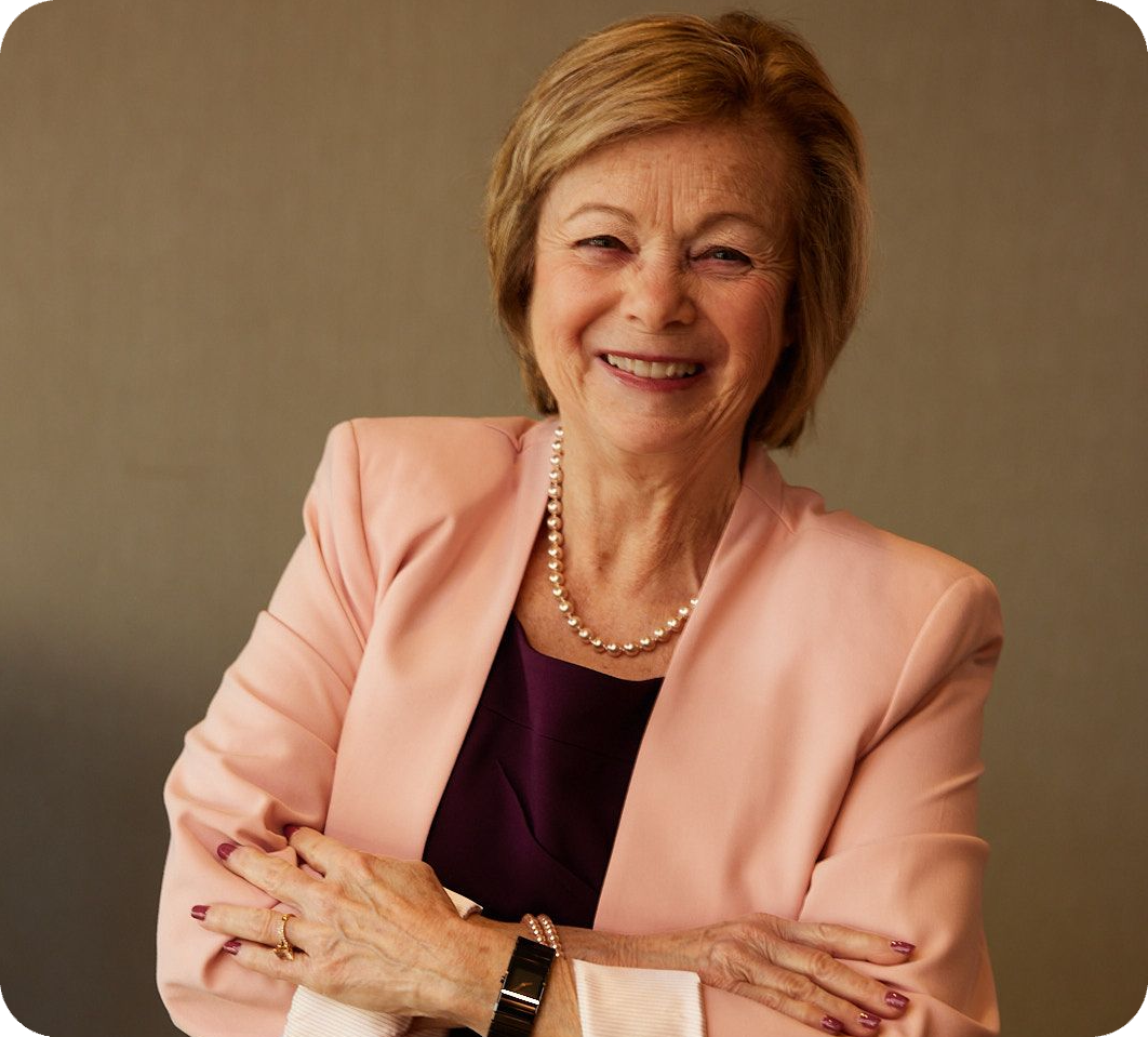 Smiling woman in a peach blazer with folded arms.